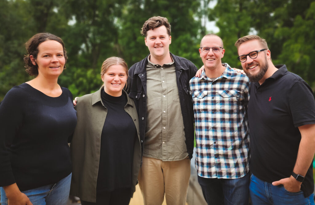 A group photo showing all five members of the team